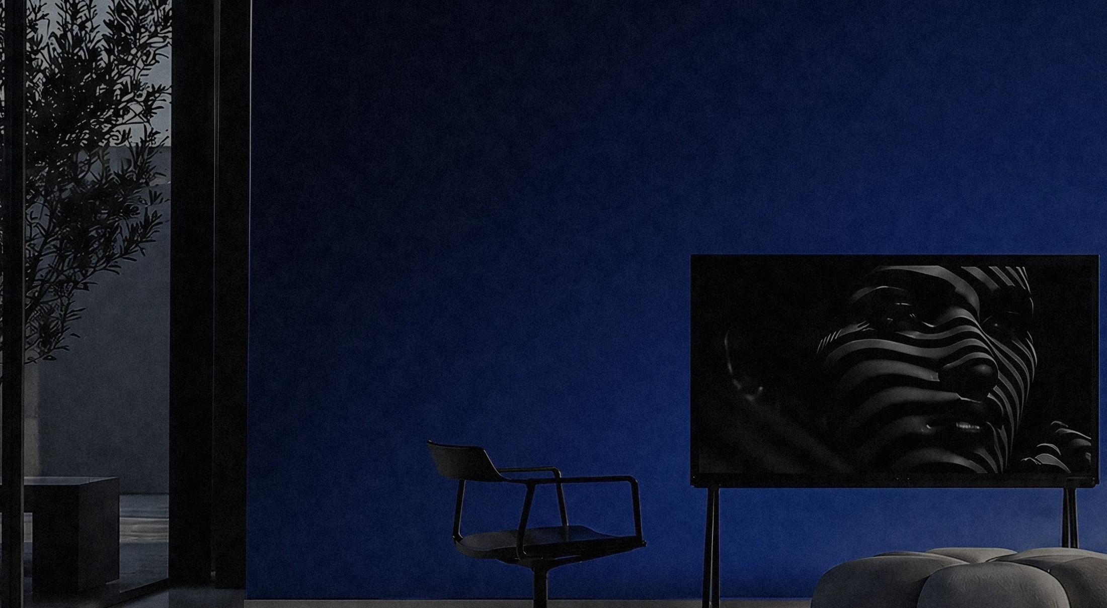 A rendered room: a deep blue wall, a single chair and a wide screen, lit from the left across a polished floor.
