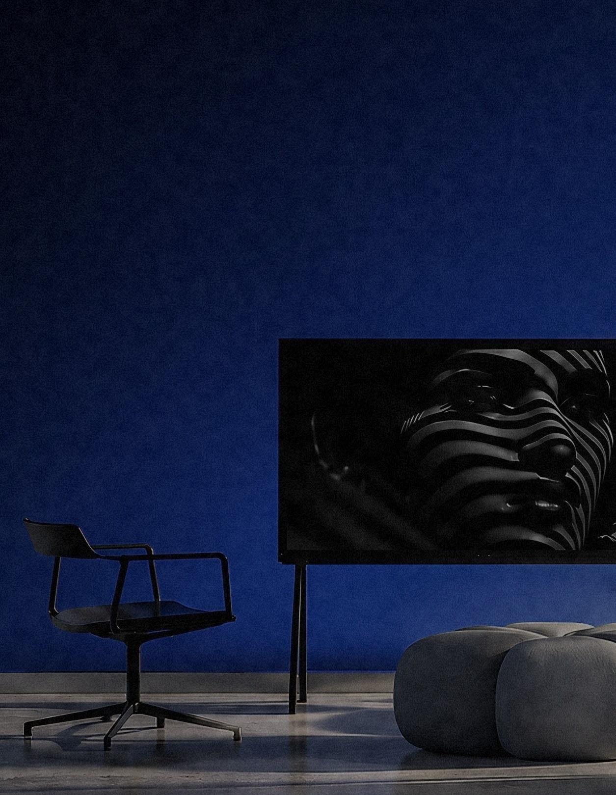 A rendered room: a deep blue wall, a single chair and a wide screen, lit from the left.