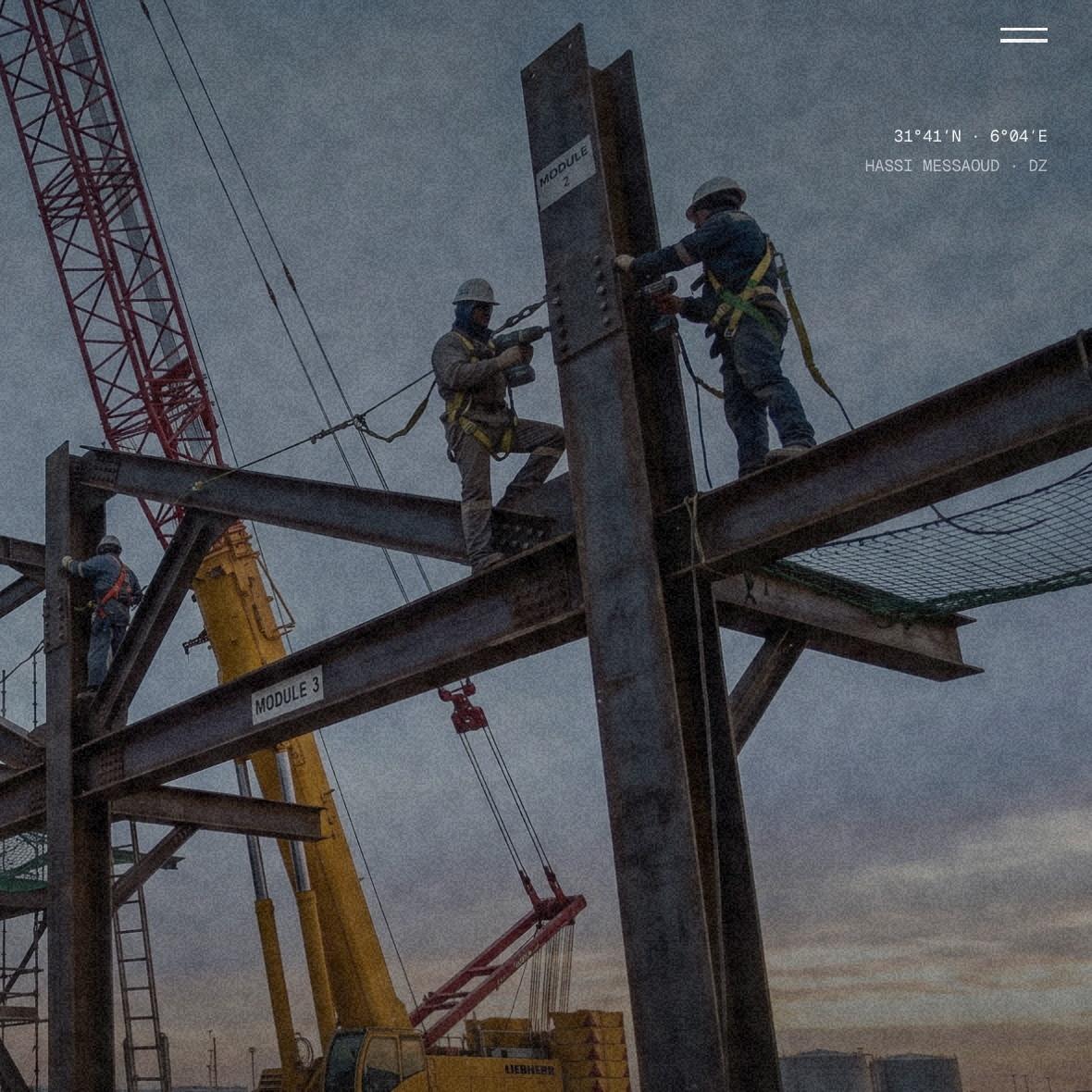 The lead image of the ABP Continental home page: steel erection at dusk, two riggers bolting a column, a crawler crane behind them, with map coordinates printed in the corner of the page.